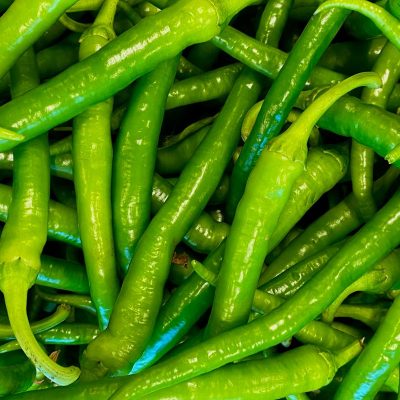 A vibrant heap of fresh green chilies, perfect for cooking or market scenes.