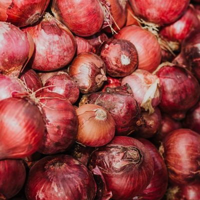 A vibrant collection of fresh red onions piled together, showcasing their rich textures and colors.